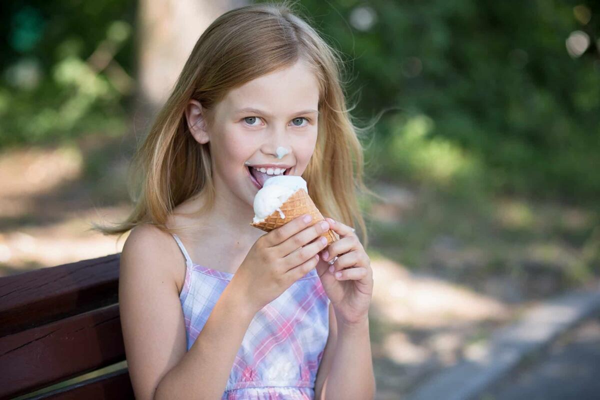 Le patatine e il gelato creano dipendenza? - Little girl happy to eat ice cream. Summer, child girl enjoying her ice cream while sitting on a bench.