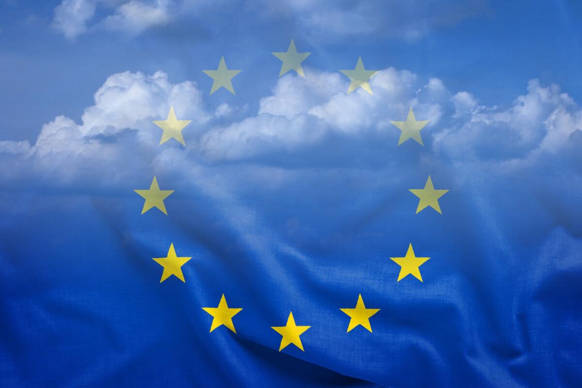 Tempesta Ciaran colpisce l'Europa: allerte meteo anche in Italia - Half-transparent EU flag with fabric blowing in the wind and white peaceful clouds in background. Full frame background concept
