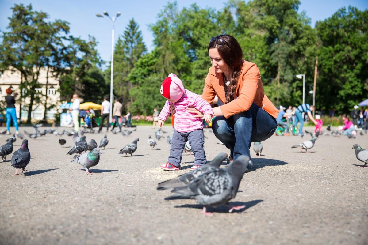 I ricordi della primissima infanzia potrebbero essere sbloccati - Child girl and mum playing with doves in city street. Use it for baby, parenting or love concept
