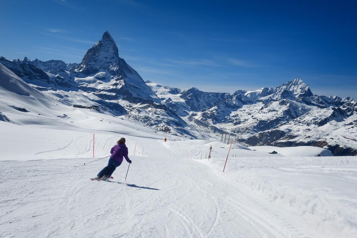 La sindaca di Valtournenche avvia le procedure per mantenere il nome storico di Breuil-Cervinia - A female skier skiing without a helmet alone on the ski slope towards majestic Matterhorn mountain on a beautiful sunny day with a thick layer of snow in ski resort Zermatt, canton of Valais in Switzerland.