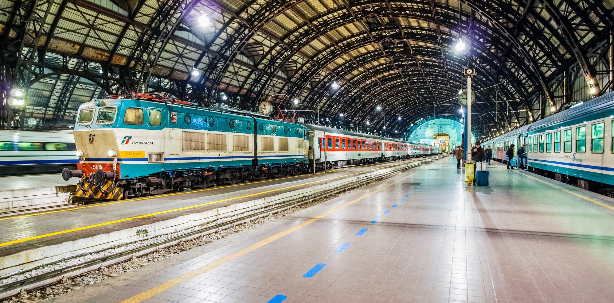 MILAN, ITALY - MARCH 22, 2009: Trains and travellers at night in Milan Stazione Centrale central railway station (HDR)