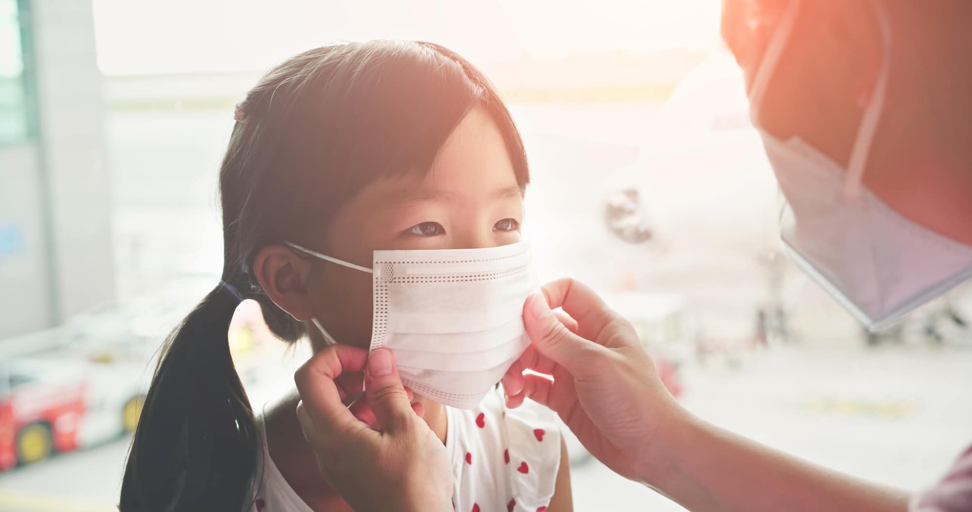 Asian parents wear masks to their children because of transmissible infectious diseases indoor in the airport
