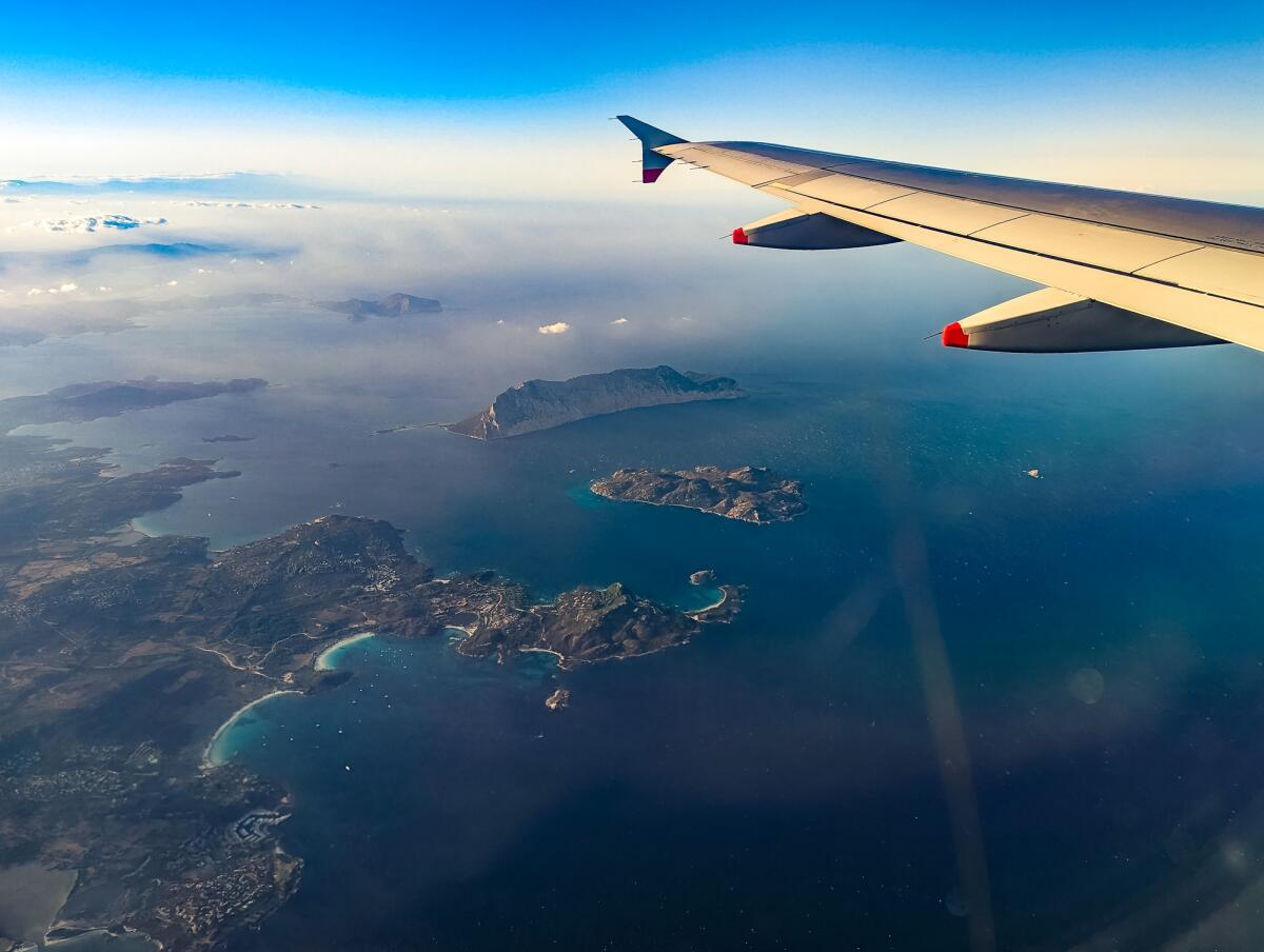 Natale 2023: prezzi astronomici per i voli in Sicilia e Sardegna - Airplane wing view of the Sardinia beaches with islands