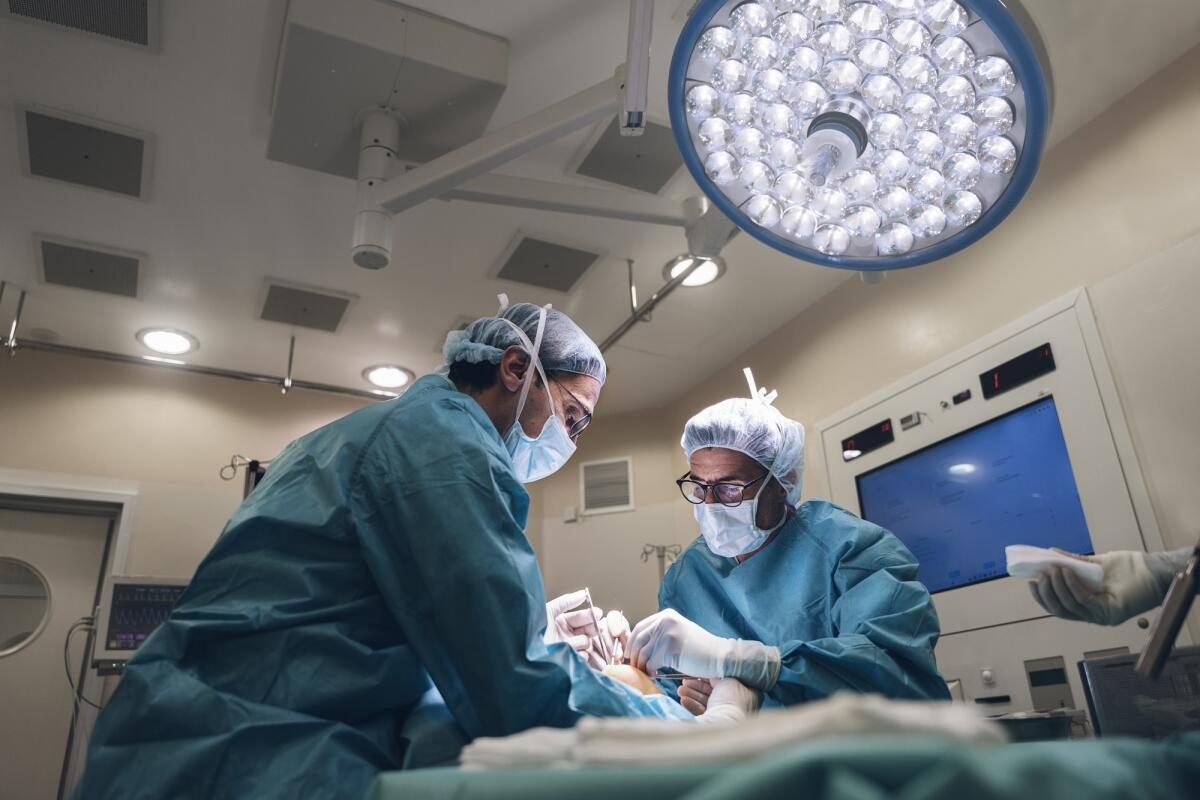 Intervento innovativo a Torino: ripristinate le funzioni di una mano paralizzata - Concentrated surgeons engaging in rescue of male patient in operating room at hospital, Surgery, medical technology, health care and disease treatment concept