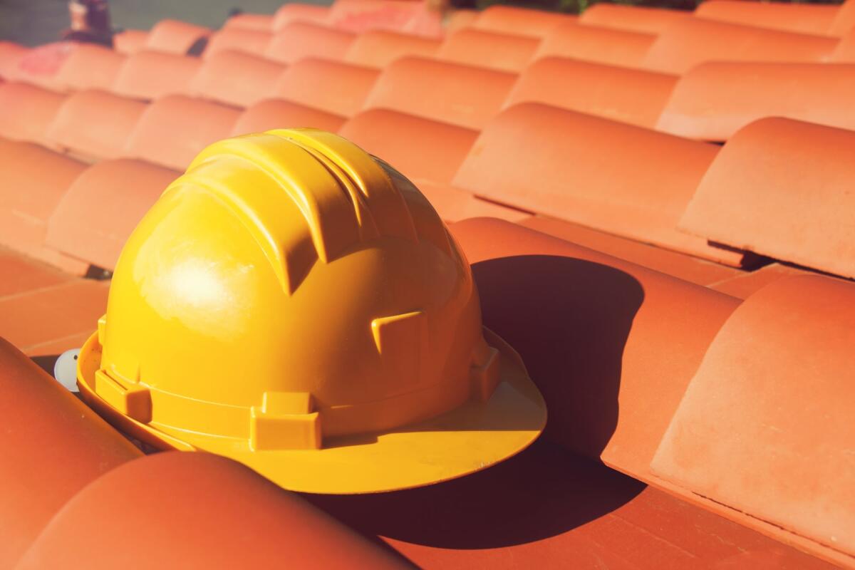 Proroga Superbonus 2023: un nuovo emendamento per garantire i lavori - Professional Yellow hard hat on a house roof . Construction site concept.