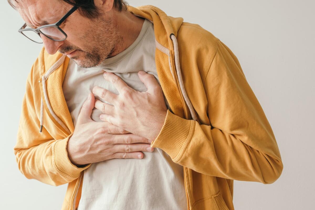Pericardite: cos'è, sintomi, cause, trattamento - Aching chest, adult male with painful grimace pressing the upper abdomen with his hands to ease pain, pericarditis concept