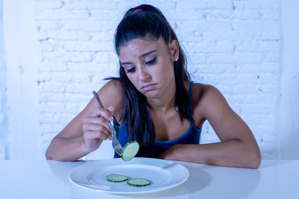 Disturbi alimentari: cause, sintomi e trattamenti - Portrait o f young attractive woman feeling sad and bored with diet not wanting to eat vegetables or healthy food in Dieting Eating Disorders and weight loss concept.
