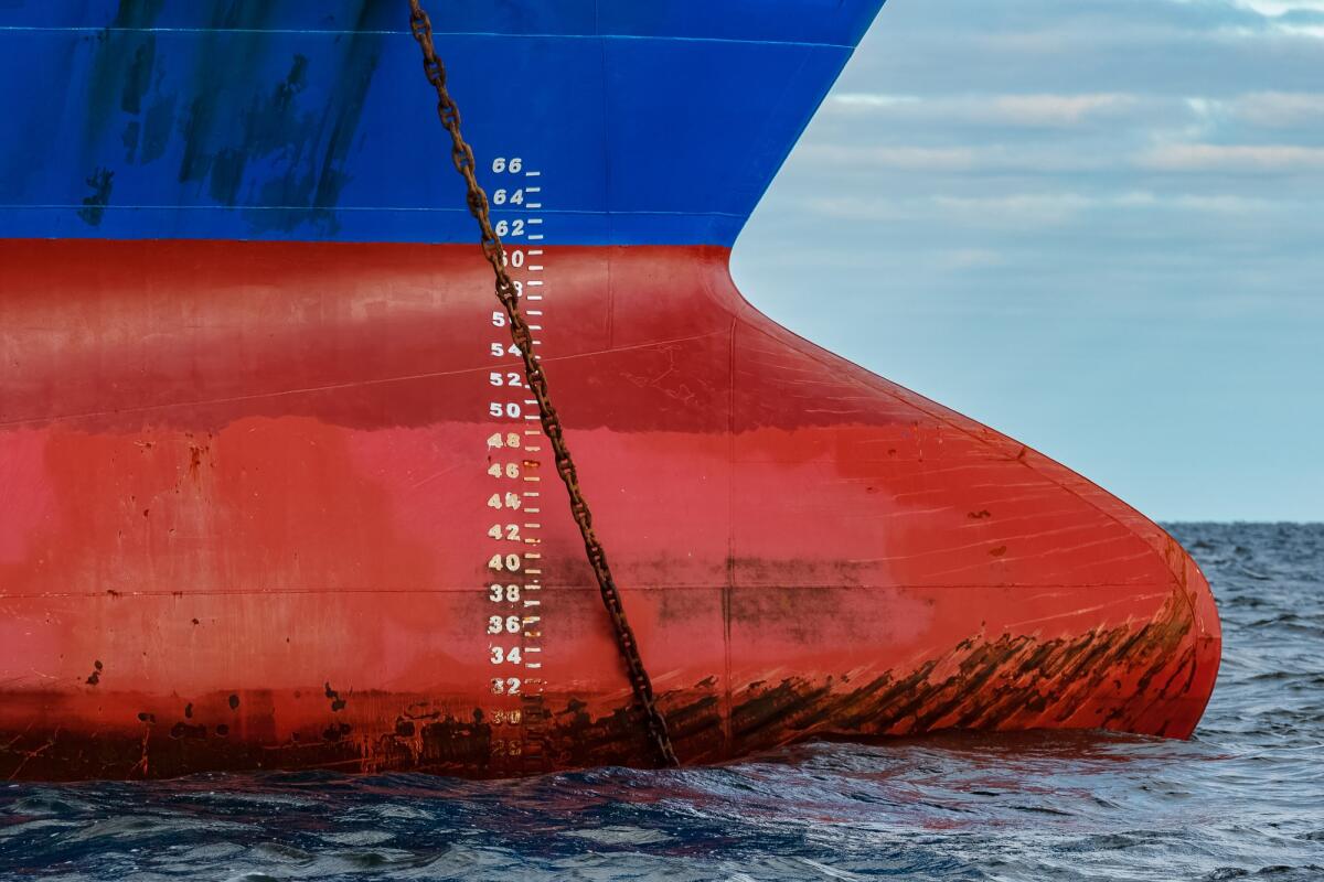 Ancore navali: dotazioni imprescindibili per una sosta sicura - Blue cargo ship moored in still Baltic sea water