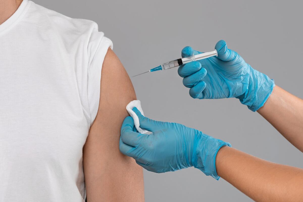 Un uomo in Germania si è sottoposto a 217 vaccinazioni contro il Covid-19 - Closeup of doctor hands injecting vaccination in arm of unrecognizable man patient in clinic, grey studio background, cropped. Vaccination against COVID-19, healthcare and medical concept