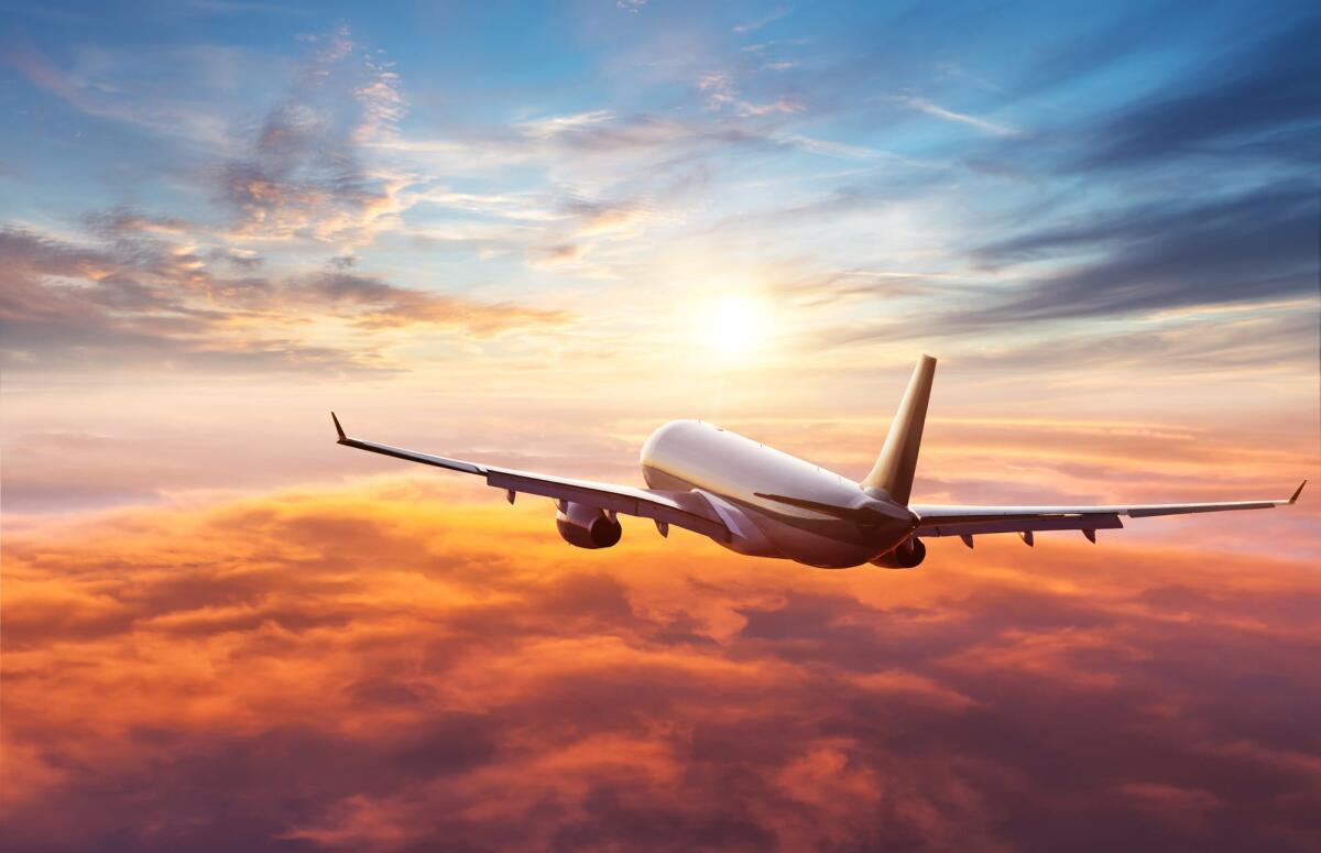 Il 2023 è stato l'anno più sicuro per il volo secondo un report dell'IATA - Passengers commercial airplane flying above clouds in sunset light. Concept of fast travel, holidays and business.