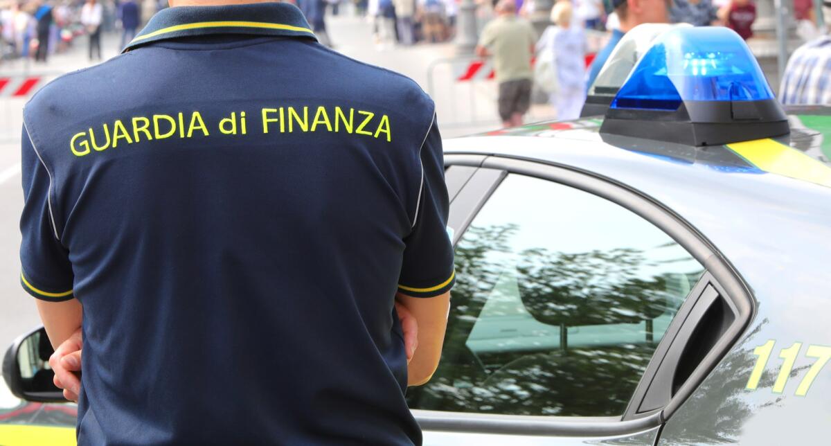 Arrestati per corruzione tre funzionari dell'Agenzia delle Entrate di Roma - Vicenza, VI, Italy - June 2, 2022: Policeman with uniform and text GUARDIA DI FINANZA that means Financial Police in italian language and the car with sirens