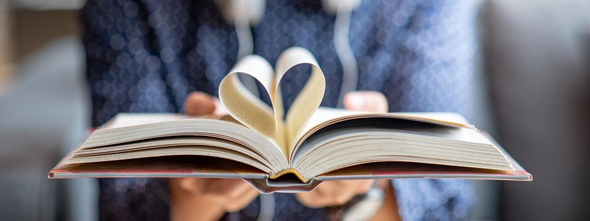 23 aprile: perché oggi si celebra la Giornata Mondiale del Libro? - Book lover or love reading concepts. Male hand holding book with heart shape page folded.