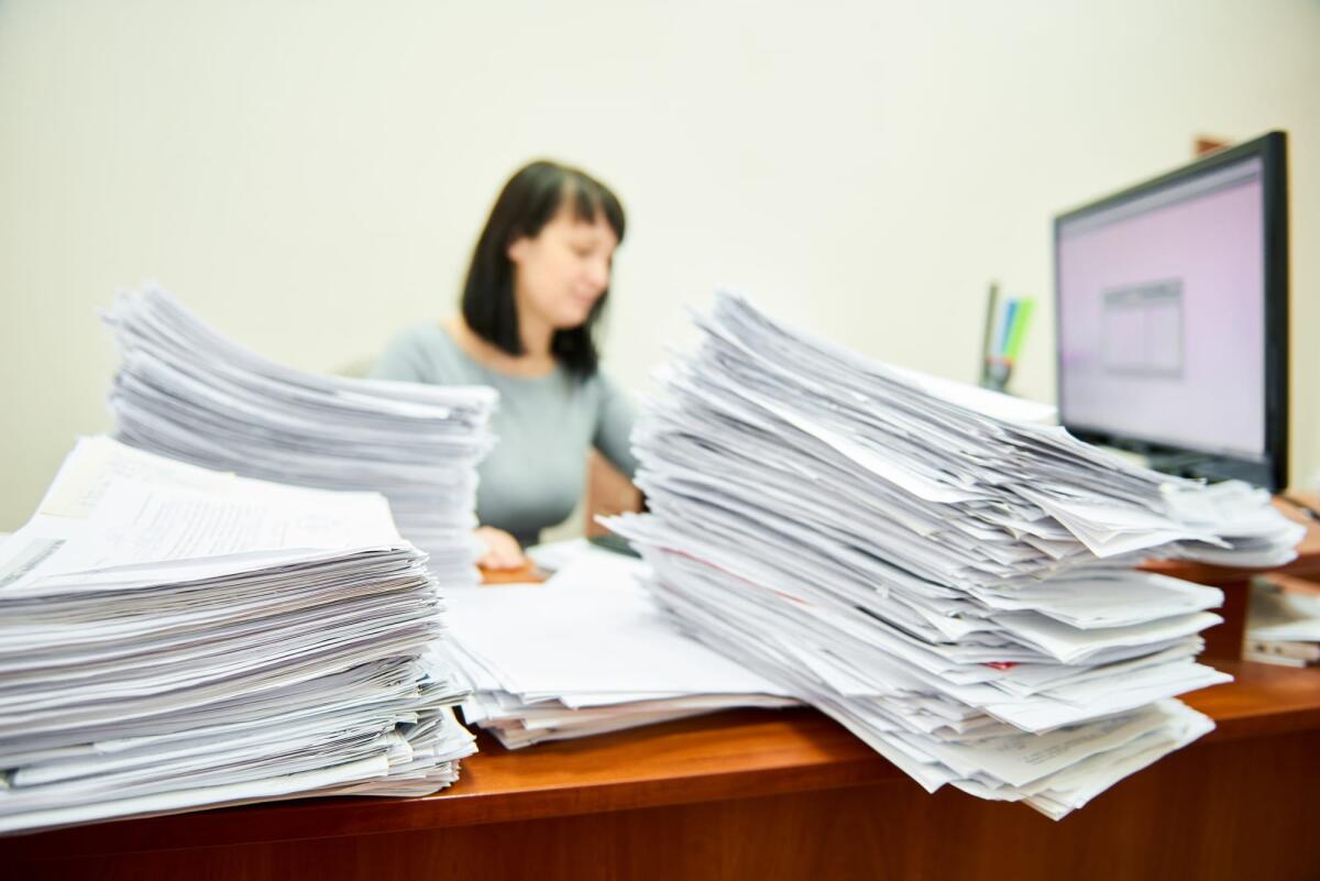 L’impatto dell’IA sul pubblico impiego: 200 mila dipendenti potrebbero essere sostituiti - Office overload. Female worker accountant with lots of paper documents