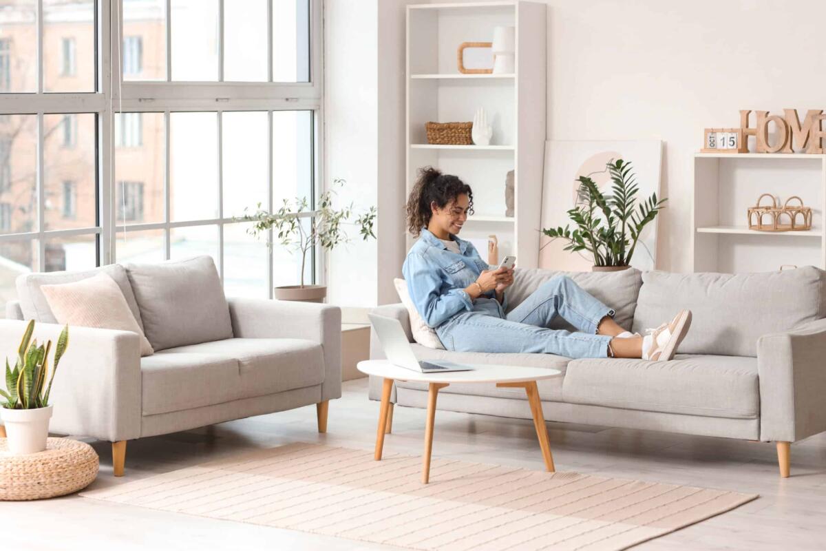 I vantaggi dell’insufflaggio: una soluzione efficace per il tuo comfort abitativo - Young African-American woman using mobile phone on sofa at home