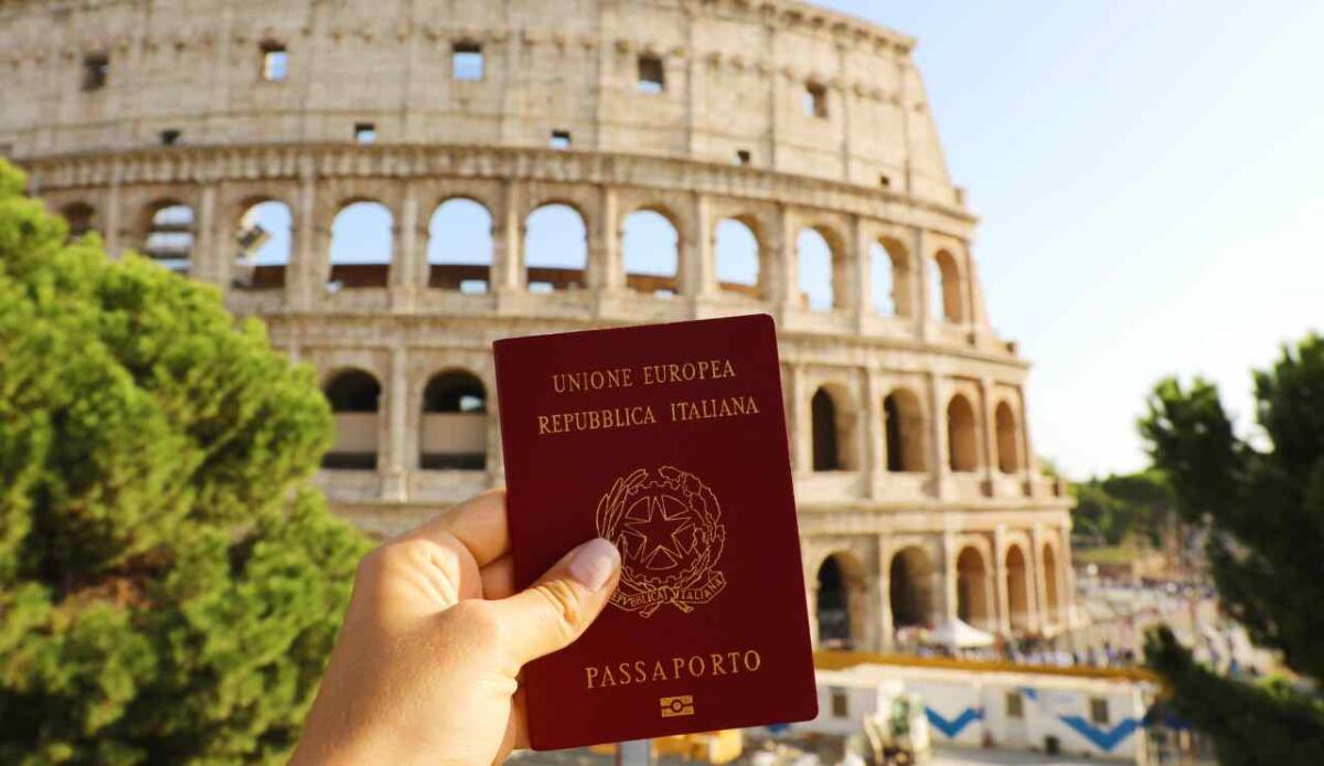 Raggiunto il quorum per il referendum sulla cittadinanza italiana: in marcia verso il cambiamento - Citizenship concept: hand hold Italian passport in front of Colosseum in Rome.