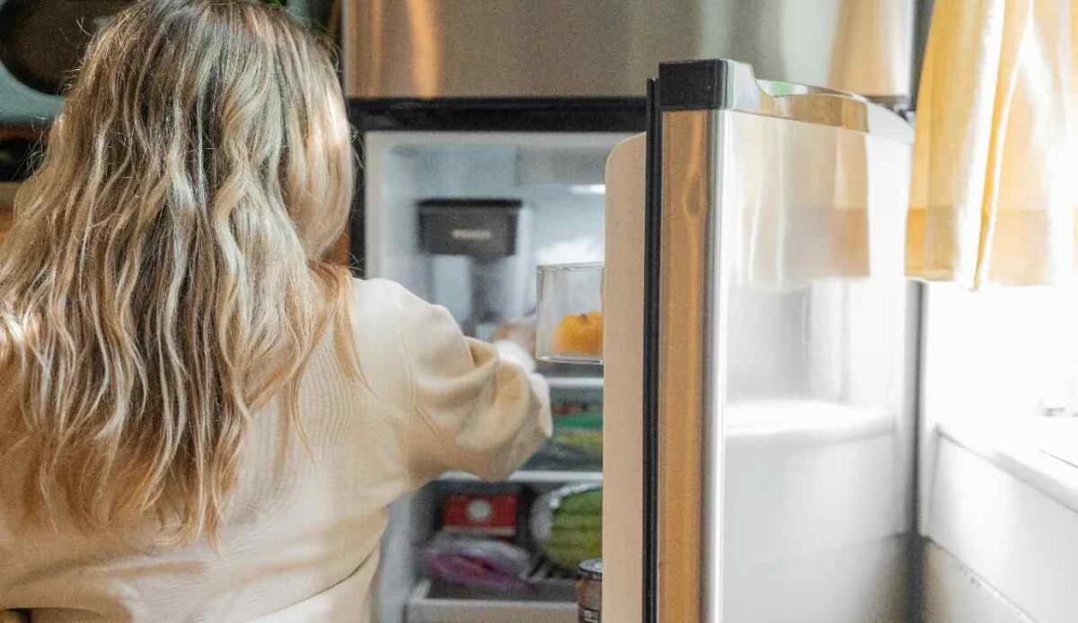 Pulizia frigorifero, non dimenticare di passare sulla parte più critica | La tua salute è a rischio - Donna che apre il frigorifero