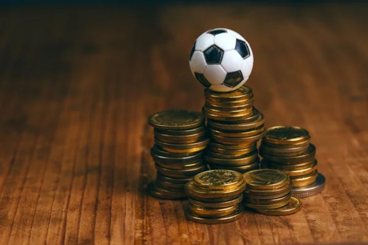 Illustrazione di una piccola palla da calcio e alcune monete (Depositphotos FOTO) - www.financecue.it