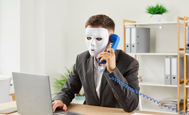 Uomo con una maschera davanti al computer (Canva foto) - www.financecue.it