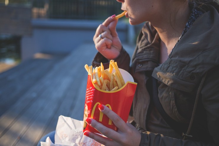 Illustrazione di una ragazza mentre mangia patatine fritte (Pixabay FOTO) - www.financecue.it