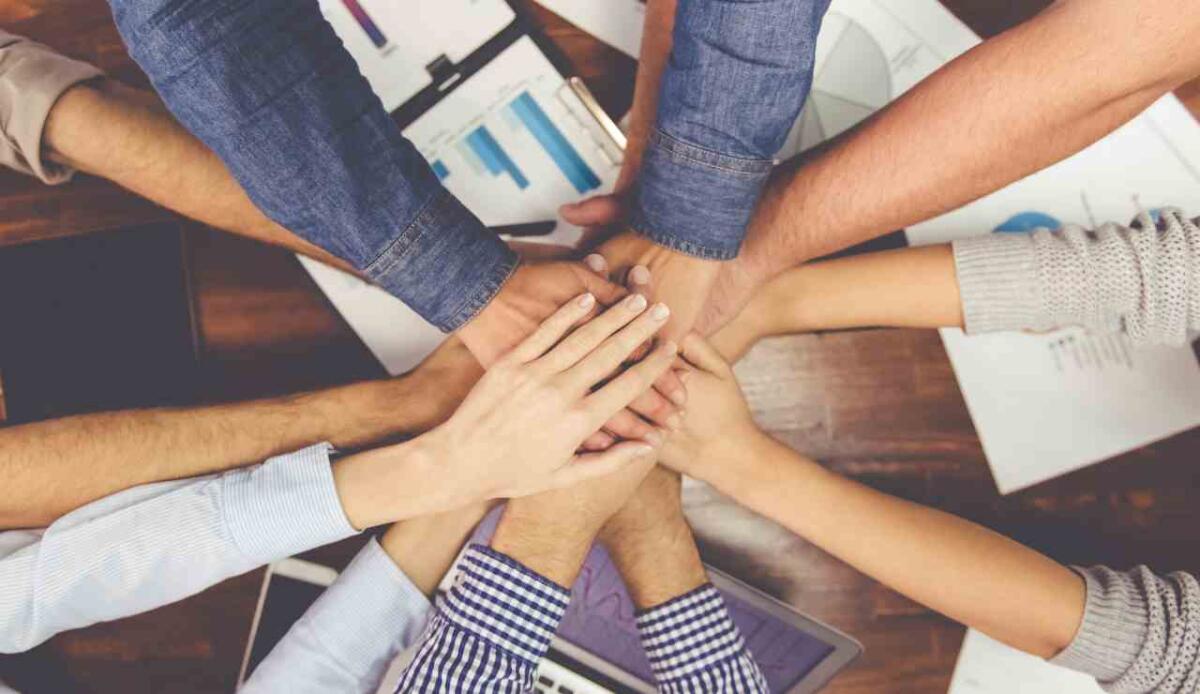Squadre eterogenee pensano fuori dagli schemi, ma trasformano meno idee in realtà - Team di lavoro eterogeneo mani al centro (Canva foto) - managementcue.it
