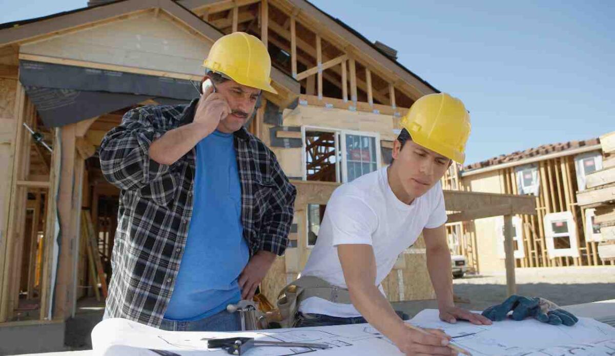 Costruire con consapevolezza: come scegliere il luogo giusto per la tua casa - Persone che costruiscono una casa  (Canva foto) - www.buildingcue.it