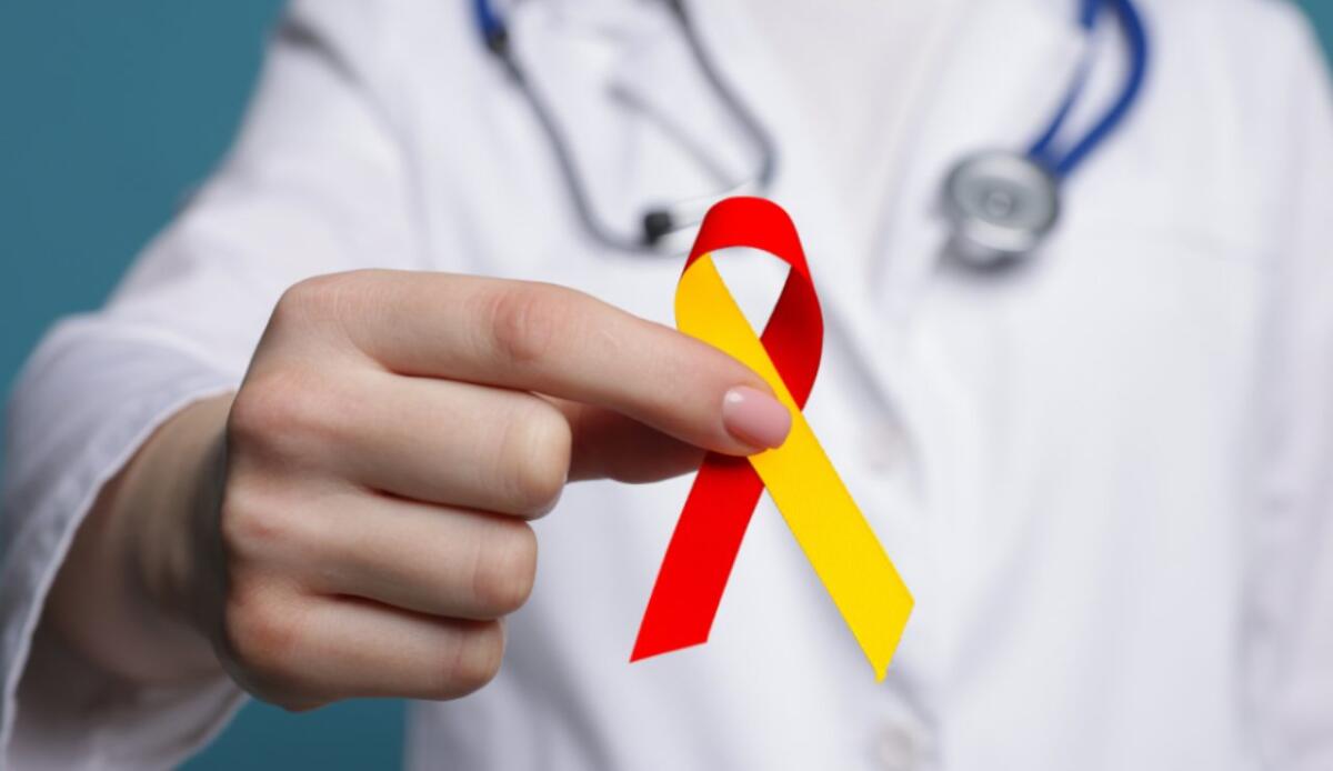 Sclerosi multipla: scoperto un bersaglio immunitario per terapie più sicure e mirate - Illustrazione di un fiocco giallo e rosso (Canva FOTO) - biomedicalcue.it